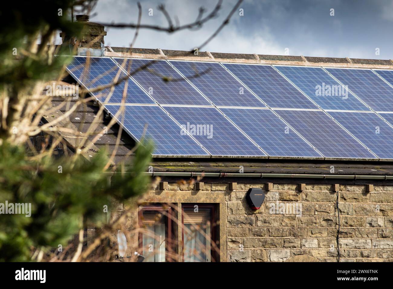 L'énergie solaire joue un rôle limité dans la production d'électricité au Royaume-Uni. Il y avait peu d'installations jusqu'en 2010, lorsque le gouvernement britannique a imposé des subventions sous la forme d'un tarif de rachat (FIT), payé par tous les consommateurs d'électricité. Au cours des années suivantes, le coût des panneaux photovoltaïques (PV) a baissé et les taux D'AJUSTEMENT pour les nouvelles installations ont été réduits progressivement jusqu'à ce que le régime ferme aux nouvelles applications en 2019. En 2023, plus de 14,4 gigawatts (GW) avaient été installés, dont un tiers solaire sur les toits. Maisons et maisons à Queensbury, West Yorkshire, Royaume-Uni avec des panneaux solaires par une journée ensoleillée. Banque D'Images