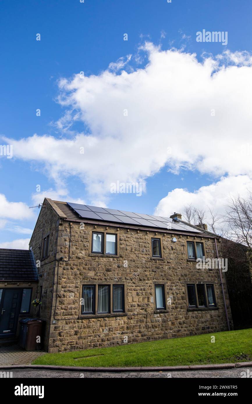 L'énergie solaire joue un rôle limité dans la production d'électricité au Royaume-Uni. Il y avait peu d'installations jusqu'en 2010, lorsque le gouvernement britannique a imposé des subventions sous la forme d'un tarif de rachat (FIT), payé par tous les consommateurs d'électricité. Au cours des années suivantes, le coût des panneaux photovoltaïques (PV) a baissé et les taux D'AJUSTEMENT pour les nouvelles installations ont été réduits progressivement jusqu'à ce que le régime ferme aux nouvelles applications en 2019. En 2023, plus de 14,4 gigawatts (GW) avaient été installés, dont un tiers solaire sur les toits. Maisons et maisons à Queensbury, West Yorkshire, Royaume-Uni avec des panneaux solaires par une journée ensoleillée. Banque D'Images