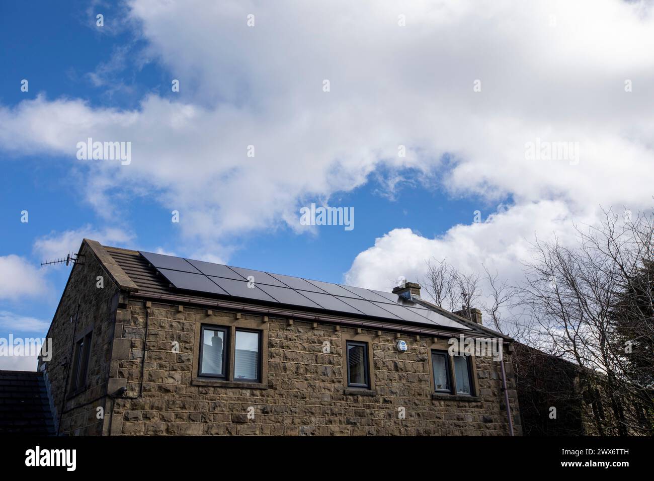 L'énergie solaire joue un rôle limité dans la production d'électricité au Royaume-Uni. Il y avait peu d'installations jusqu'en 2010, lorsque le gouvernement britannique a imposé des subventions sous la forme d'un tarif de rachat (FIT), payé par tous les consommateurs d'électricité. Au cours des années suivantes, le coût des panneaux photovoltaïques (PV) a baissé et les taux D'AJUSTEMENT pour les nouvelles installations ont été réduits progressivement jusqu'à ce que le régime ferme aux nouvelles applications en 2019. En 2023, plus de 14,4 gigawatts (GW) avaient été installés, dont un tiers solaire sur les toits. Maisons et maisons à Queensbury, West Yorkshire, Royaume-Uni avec des panneaux solaires par une journée ensoleillée. Banque D'Images