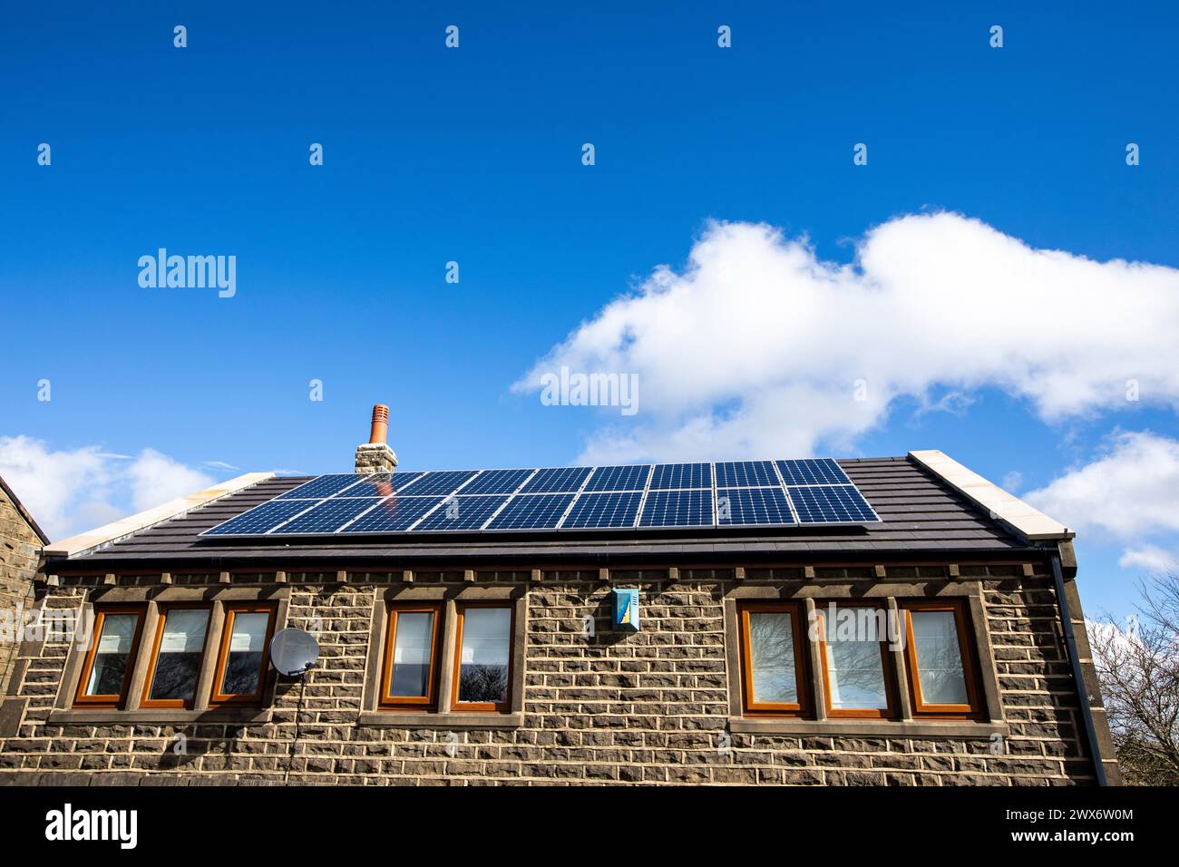 L'énergie solaire joue un rôle limité dans la production d'électricité au Royaume-Uni. Il y avait peu d'installations jusqu'en 2010, lorsque le gouvernement britannique a imposé des subventions sous la forme d'un tarif de rachat (FIT), payé par tous les consommateurs d'électricité. Au cours des années suivantes, le coût des panneaux photovoltaïques (PV) a baissé et les taux D'AJUSTEMENT pour les nouvelles installations ont été réduits progressivement jusqu'à ce que le régime ferme aux nouvelles applications en 2019. En 2023, plus de 14,4 gigawatts (GW) avaient été installés, dont un tiers solaire sur les toits. Maisons et maisons à Queensbury, West Yorkshire, Royaume-Uni avec des panneaux solaires par une journée ensoleillée. Banque D'Images
