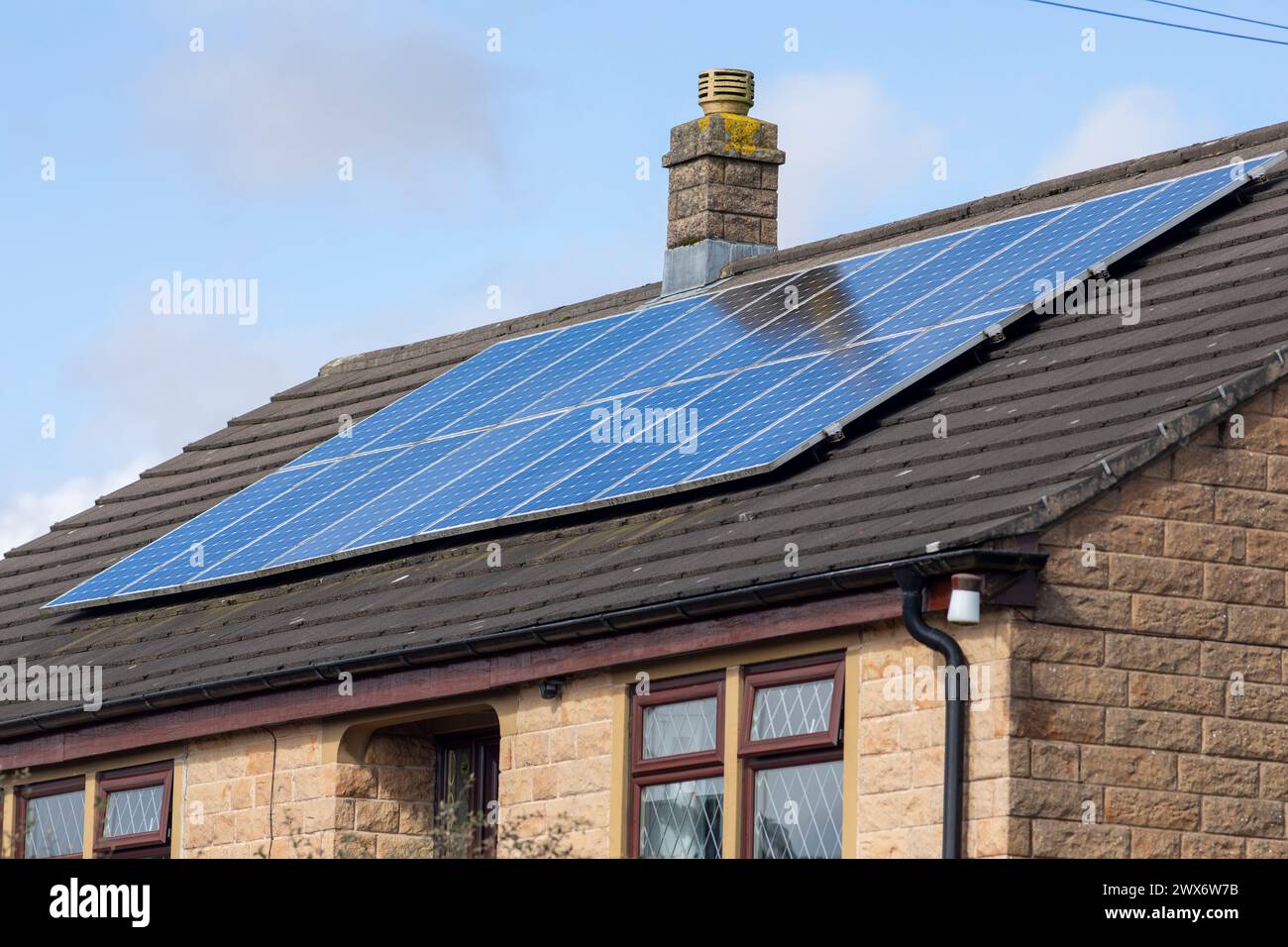 L'énergie solaire joue un rôle limité dans la production d'électricité au Royaume-Uni. Il y avait peu d'installations jusqu'en 2010, lorsque le gouvernement britannique a imposé des subventions sous la forme d'un tarif de rachat (FIT), payé par tous les consommateurs d'électricité. Au cours des années suivantes, le coût des panneaux photovoltaïques (PV) a baissé et les taux D'AJUSTEMENT pour les nouvelles installations ont été réduits progressivement jusqu'à ce que le régime ferme aux nouvelles applications en 2019. En 2023, plus de 14,4 gigawatts (GW) avaient été installés, dont un tiers solaire sur les toits. Maisons et maisons à Queensbury, West Yorkshire, Royaume-Uni avec des panneaux solaires par une journée ensoleillée. Banque D'Images