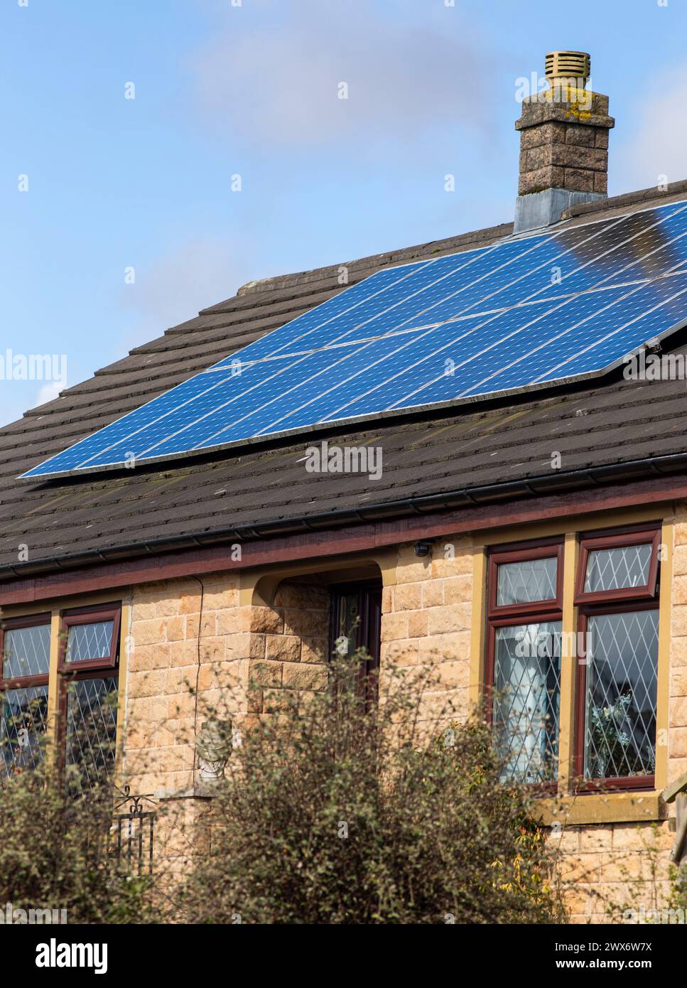 L'énergie solaire joue un rôle limité dans la production d'électricité au Royaume-Uni. Il y avait peu d'installations jusqu'en 2010, lorsque le gouvernement britannique a imposé des subventions sous la forme d'un tarif de rachat (FIT), payé par tous les consommateurs d'électricité. Au cours des années suivantes, le coût des panneaux photovoltaïques (PV) a baissé et les taux D'AJUSTEMENT pour les nouvelles installations ont été réduits progressivement jusqu'à ce que le régime ferme aux nouvelles applications en 2019. En 2023, plus de 14,4 gigawatts (GW) avaient été installés, dont un tiers solaire sur les toits. Maisons et maisons à Queensbury, West Yorkshire, Royaume-Uni avec des panneaux solaires par une journée ensoleillée. Banque D'Images