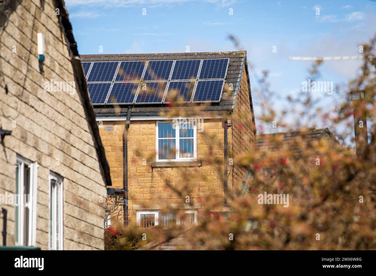 L'énergie solaire joue un rôle limité dans la production d'électricité au Royaume-Uni. Il y avait peu d'installations jusqu'en 2010, lorsque le gouvernement britannique a imposé des subventions sous la forme d'un tarif de rachat (FIT), payé par tous les consommateurs d'électricité. Au cours des années suivantes, le coût des panneaux photovoltaïques (PV) a baissé et les taux D'AJUSTEMENT pour les nouvelles installations ont été réduits progressivement jusqu'à ce que le régime ferme aux nouvelles applications en 2019. En 2023, plus de 14,4 gigawatts (GW) avaient été installés, dont un tiers solaire sur les toits. Maisons et maisons à Queensbury, West Yorkshire, Royaume-Uni avec des panneaux solaires par une journée ensoleillée. Banque D'Images