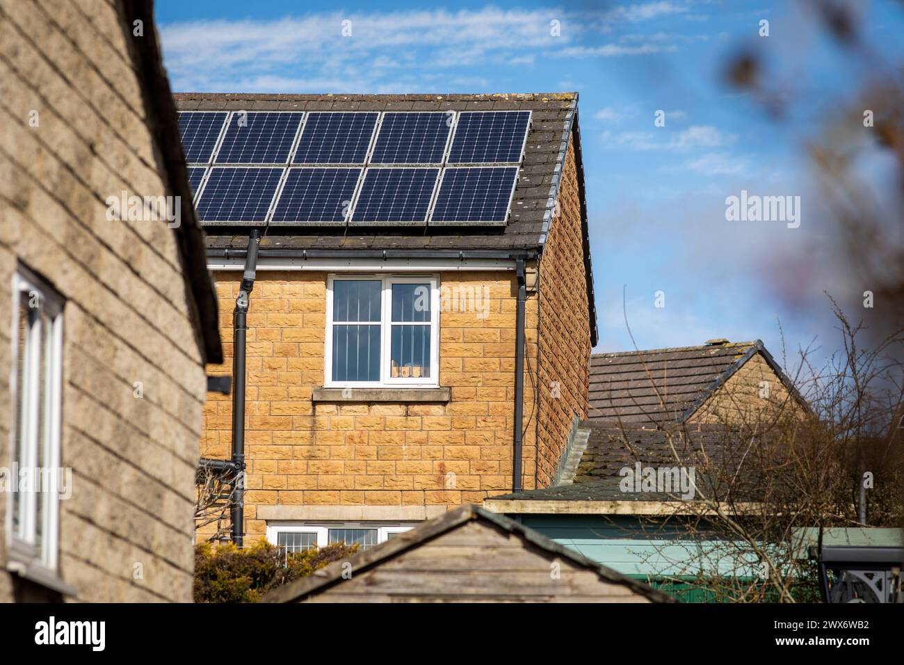 L'énergie solaire joue un rôle limité dans la production d'électricité au Royaume-Uni. Il y avait peu d'installations jusqu'en 2010, lorsque le gouvernement britannique a imposé des subventions sous la forme d'un tarif de rachat (FIT), payé par tous les consommateurs d'électricité. Au cours des années suivantes, le coût des panneaux photovoltaïques (PV) a baissé et les taux D'AJUSTEMENT pour les nouvelles installations ont été réduits progressivement jusqu'à ce que le régime ferme aux nouvelles applications en 2019. En 2023, plus de 14,4 gigawatts (GW) avaient été installés, dont un tiers solaire sur les toits. Maisons et maisons à Queensbury, West Yorkshire, Royaume-Uni avec des panneaux solaires par une journée ensoleillée. Banque D'Images