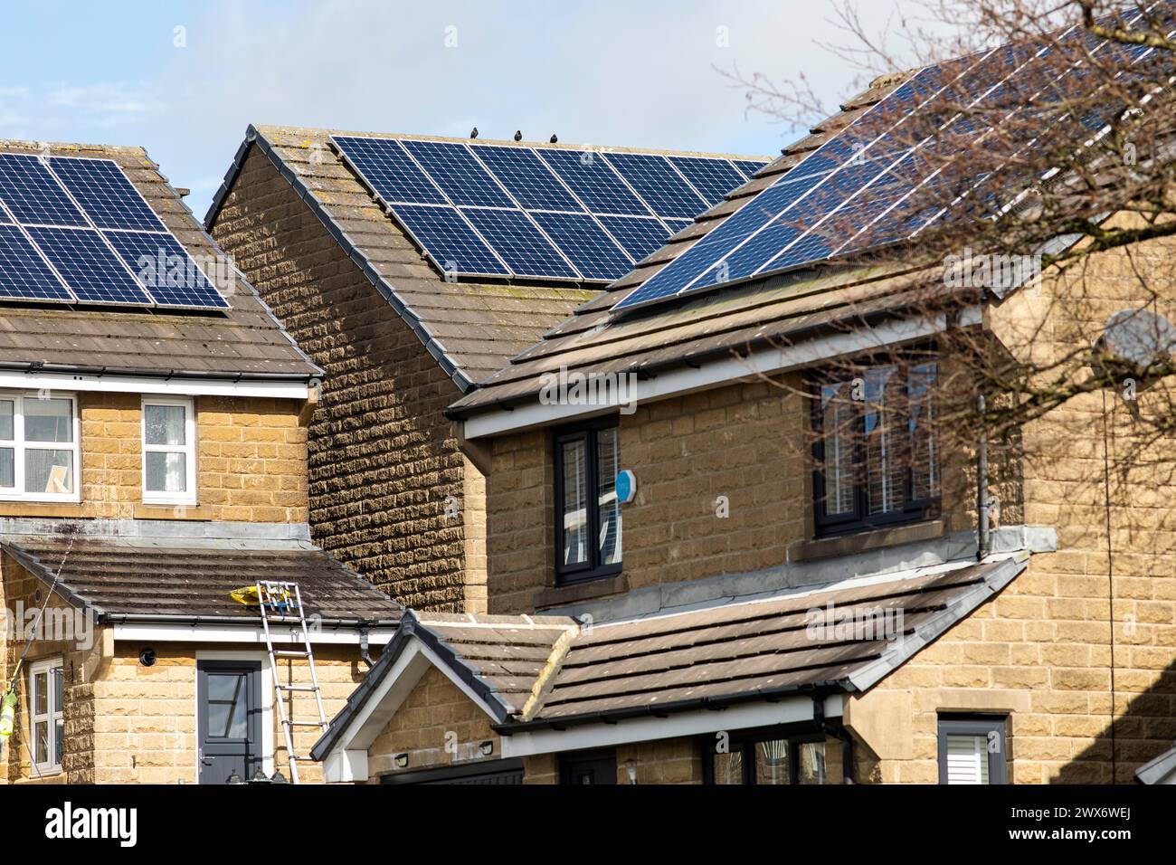 L'énergie solaire joue un rôle limité dans la production d'électricité au Royaume-Uni. Il y avait peu d'installations jusqu'en 2010, lorsque le gouvernement britannique a imposé des subventions sous la forme d'un tarif de rachat (FIT), payé par tous les consommateurs d'électricité. Au cours des années suivantes, le coût des panneaux photovoltaïques (PV) a baissé et les taux D'AJUSTEMENT pour les nouvelles installations ont été réduits progressivement jusqu'à ce que le régime ferme aux nouvelles applications en 2019. En 2023, plus de 14,4 gigawatts (GW) avaient été installés, dont un tiers solaire sur les toits. Maisons et maisons à Queensbury, West Yorkshire, Royaume-Uni avec des panneaux solaires par une journée ensoleillée. Banque D'Images