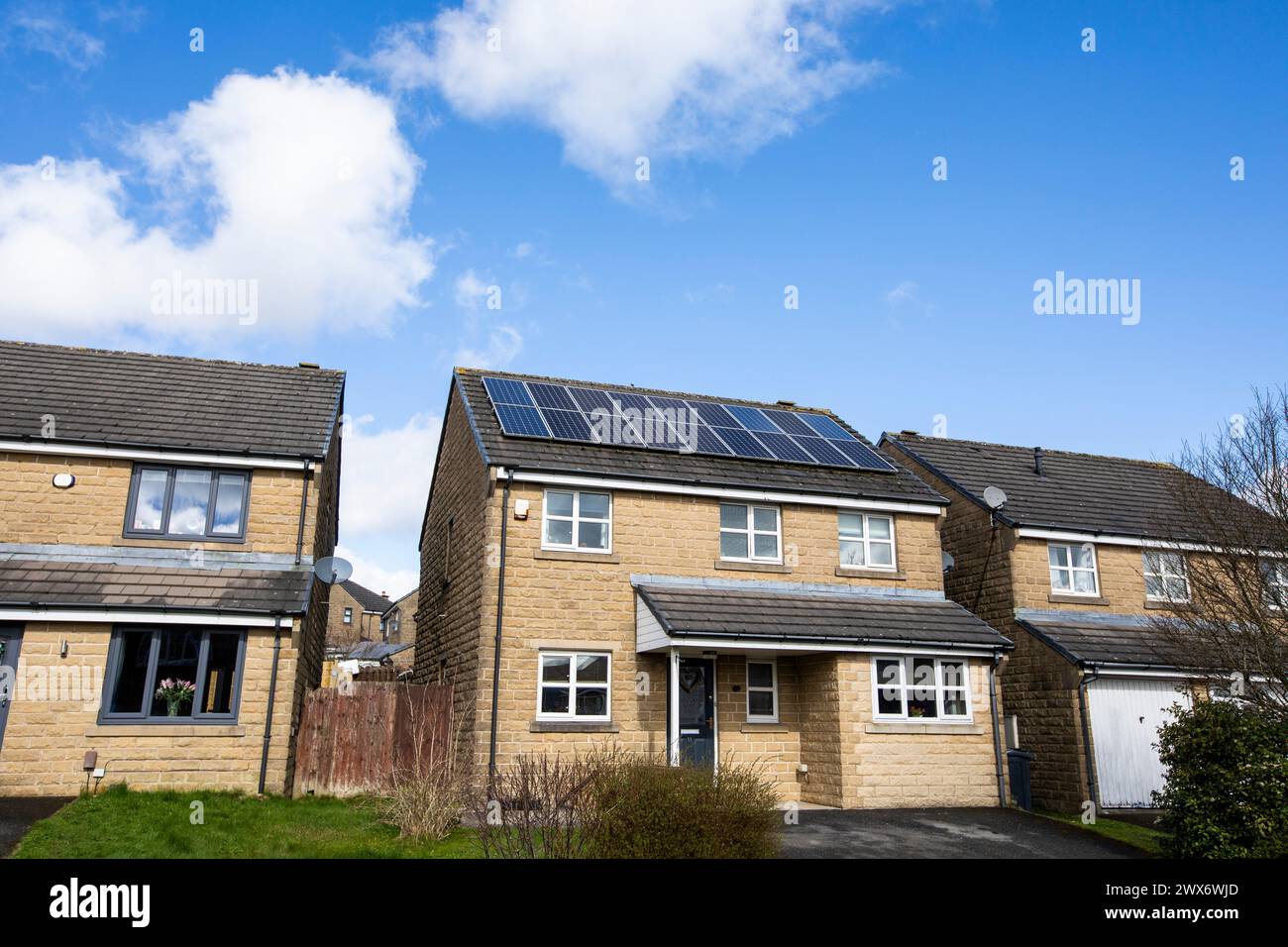 L'énergie solaire joue un rôle limité dans la production d'électricité au Royaume-Uni. Il y avait peu d'installations jusqu'en 2010, lorsque le gouvernement britannique a imposé des subventions sous la forme d'un tarif de rachat (FIT), payé par tous les consommateurs d'électricité. Au cours des années suivantes, le coût des panneaux photovoltaïques (PV) a baissé et les taux D'AJUSTEMENT pour les nouvelles installations ont été réduits progressivement jusqu'à ce que le régime ferme aux nouvelles applications en 2019. En 2023, plus de 14,4 gigawatts (GW) avaient été installés, dont un tiers solaire sur les toits. Maisons et maisons à Queensbury, West Yorkshire, Royaume-Uni avec des panneaux solaires par une journée ensoleillée. Banque D'Images
