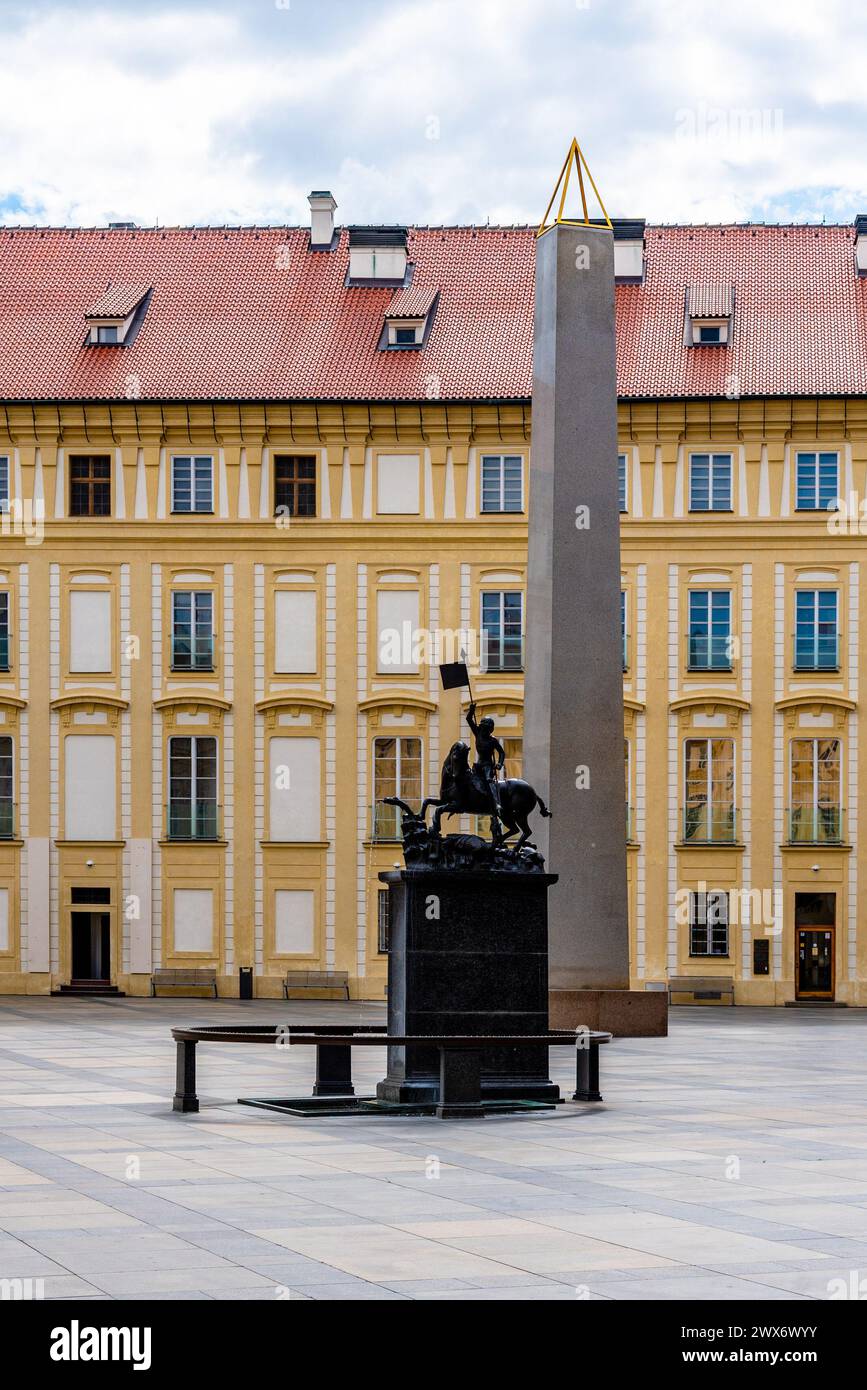 Saint George à cheval, triomphant d'un dragon, se dresse devant un obélisque dans la cour historique du château de Prague avec une élégante façade en toile de fond. Prague, Tchéquie Banque D'Images