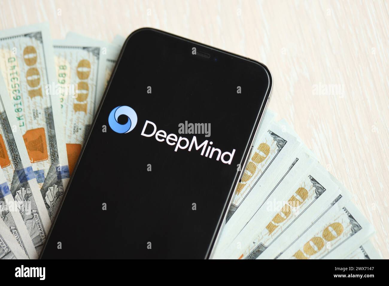 KIEV, UKRAINE - 17 MARS 2024 logo DeepMind sur l'écran d'affichage de l'iPhone avec plusieurs centaines de billets de dollars. Moteur d'intelligence artificielle Banque D'Images