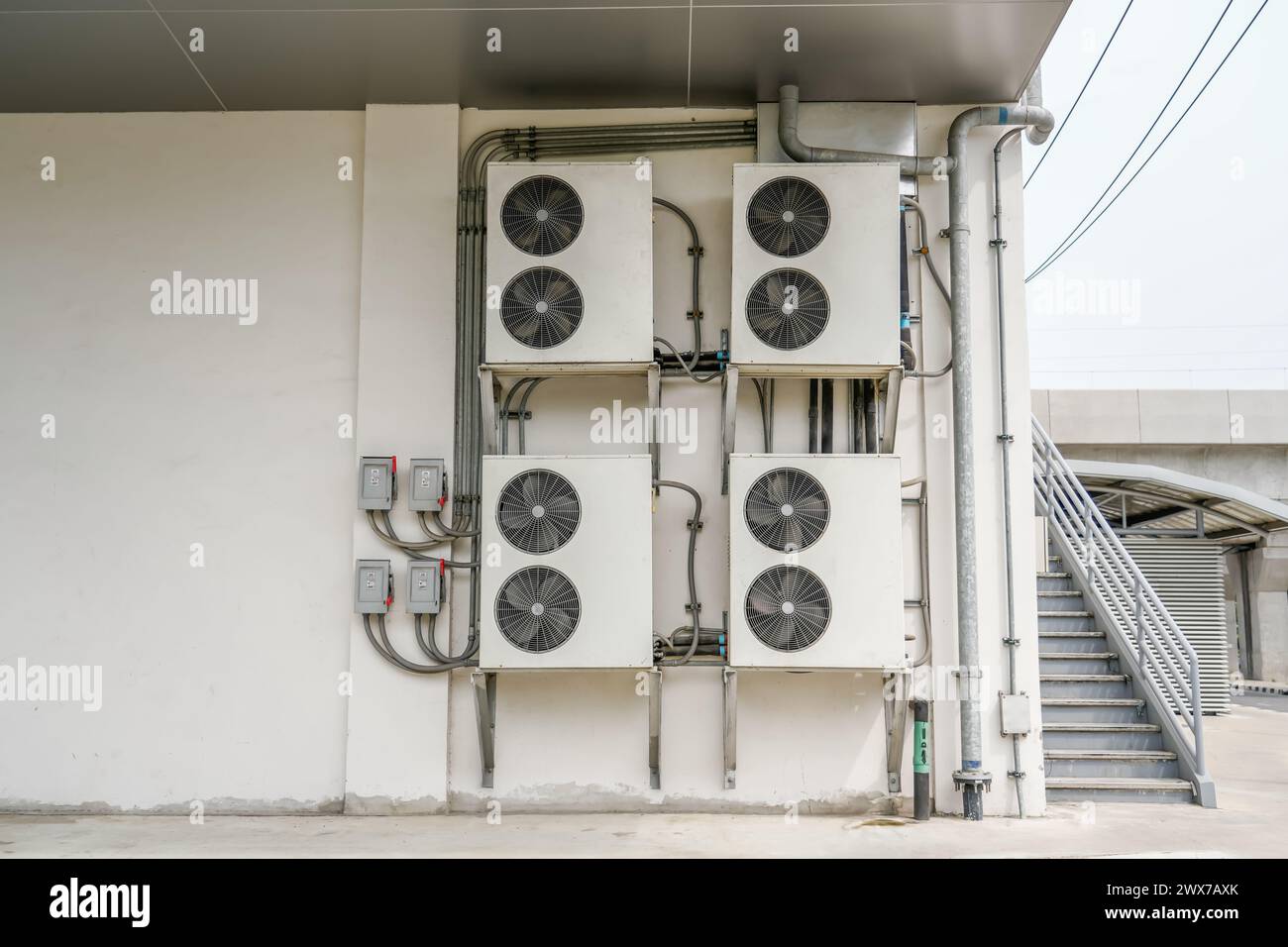 Unité de condensation de climatiseur installer sur le mur côté porte extérieure pour la ventilation de la chaleur du système de réfrigération près de l'escalier. Banque D'Images