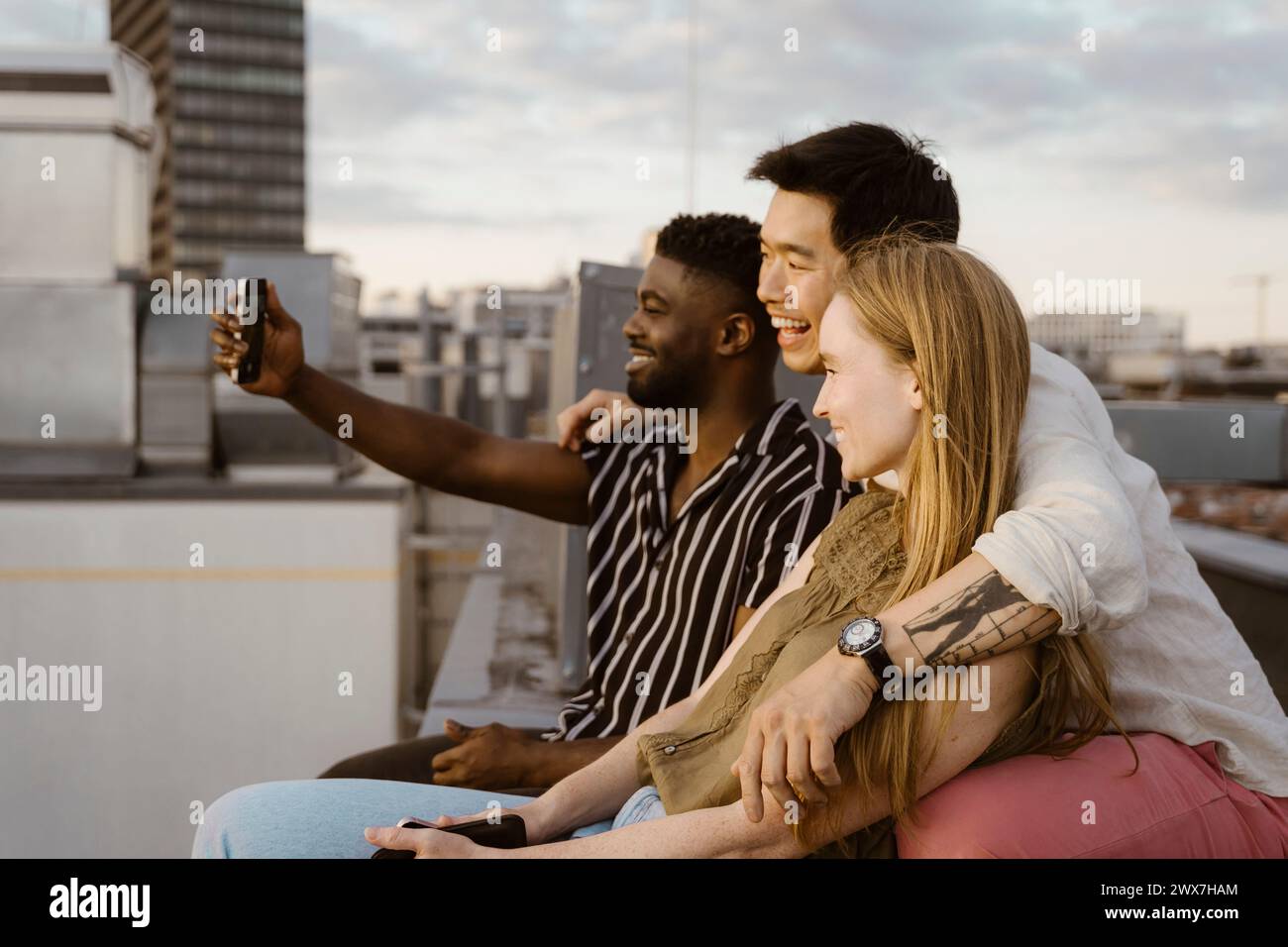 Jeune homme prenant selfie avec des amis par téléphone intelligent tout en étant assis sur la terrasse Banque D'Images