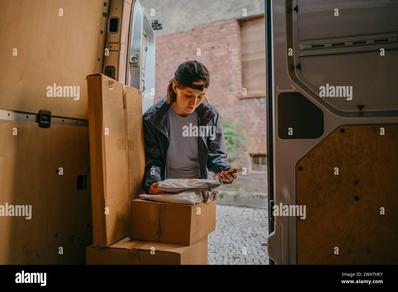 Livreur de courrier féminin faisant l'inventaire des colis dans le coffre de fourgonnette Banque D'Images