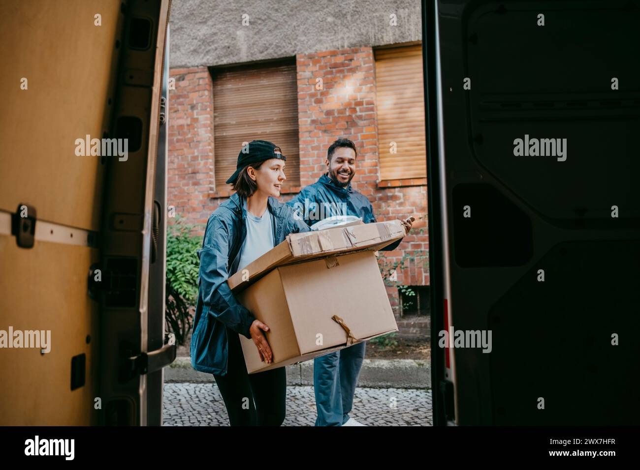 Collègues accoucheurs hommes et femmes transportant des boîtes vus du coffre de fourgonnette Banque D'Images