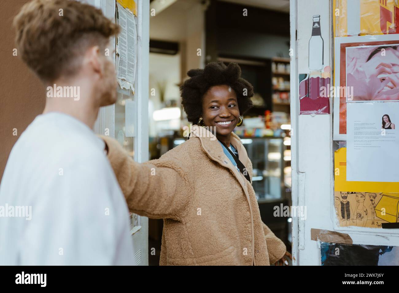 Petite amie souriante regardant petit ami en entrant dans le supermarché Banque D'Images