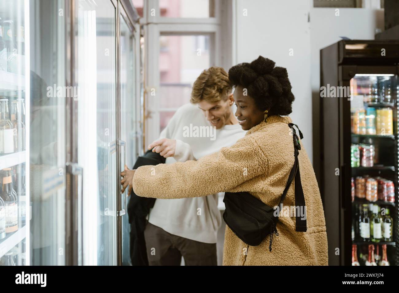 Couple multiracial achetant des boissons de la section réfrigérée tout en faisant du shopping au supermarché Banque D'Images