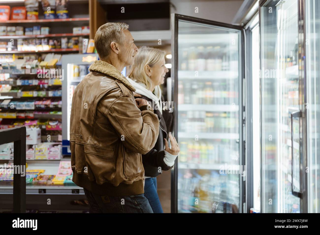 Couple mature souriant faisant du shopping de la section réfrigérée au supermarché Banque D'Images