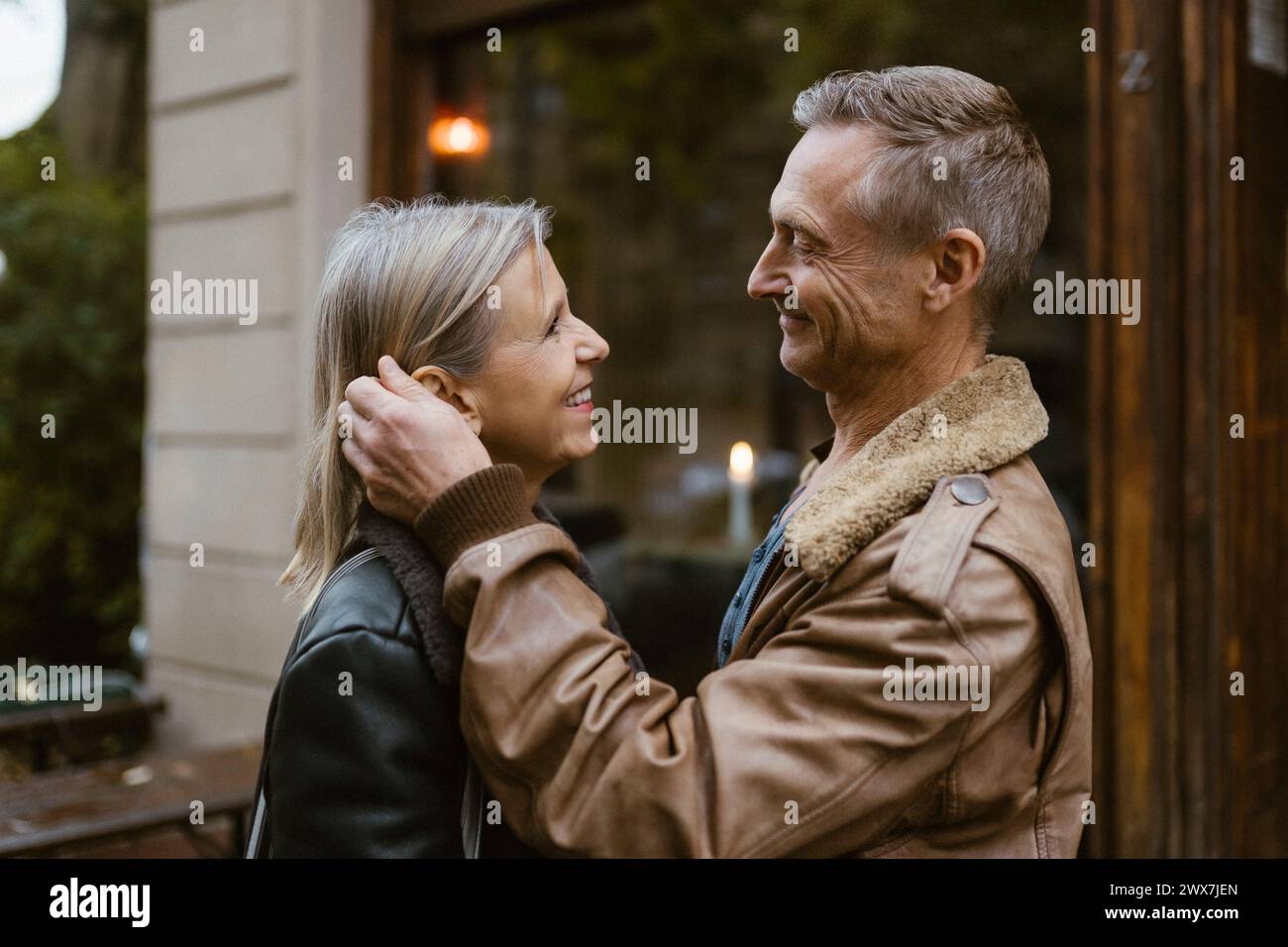 Vue latérale d'un homme souriant caressant une femme debout devant le restaurant Banque D'Images