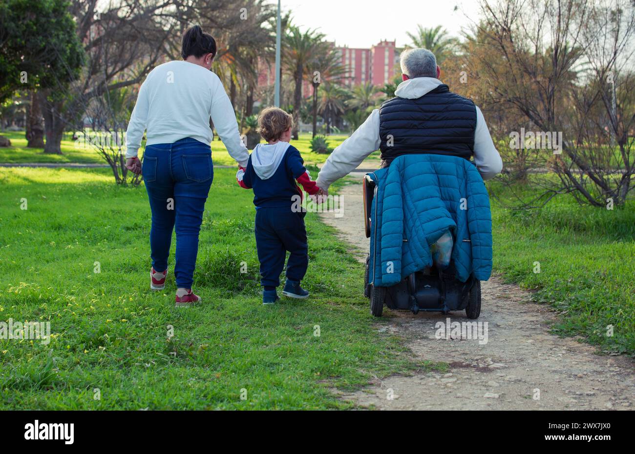 malgré être en fauteuil roulant n'est pas un problème, marcher main dans la main avec sa famille dans le parc. Banque D'Images