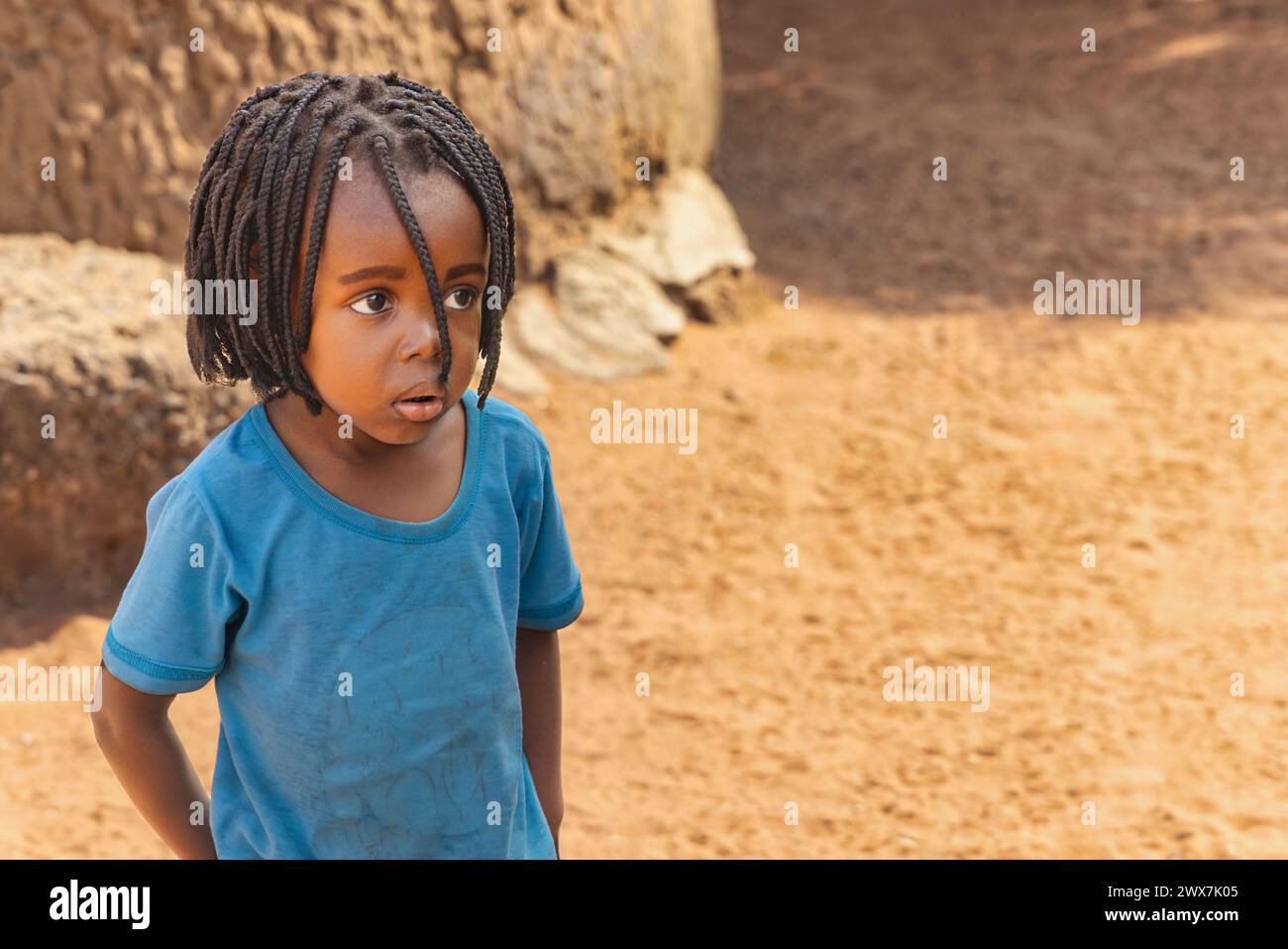 portrait d'une fille africaine avec des tresses jouant dans la cour, vie de village africain Banque D'Images