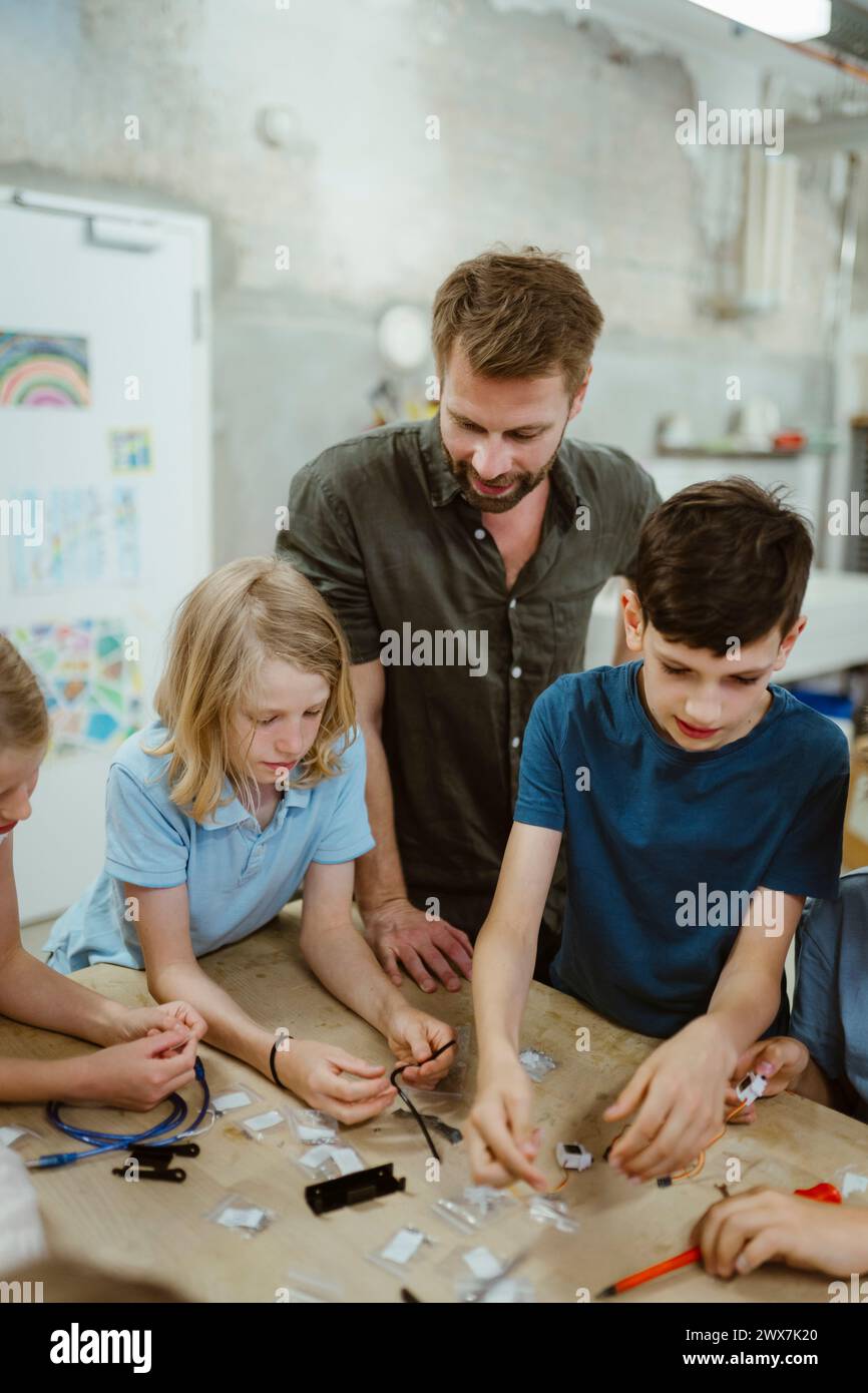 Enseignant masculin assistant les élèves pendant le cours de technologie Banque D'Images