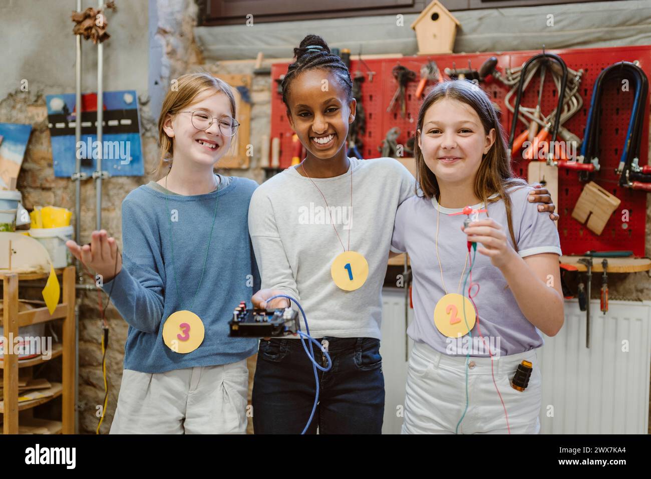 Portrait d'étudiantes heureuses montrant des pièces électriques lors d'un atelier technologique à l'école Banque D'Images