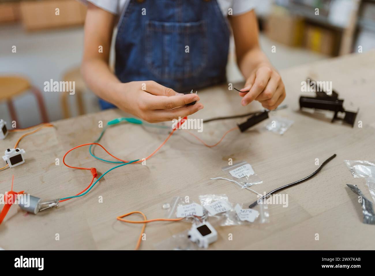 Section médiane de l'élève branchant les fils électriques sur la table à l'atelier de l'école Banque D'Images
