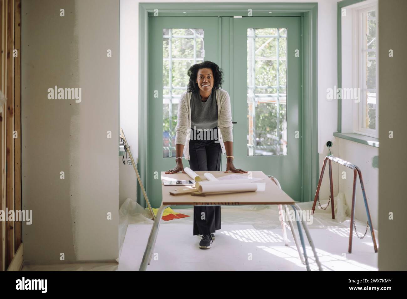 Portrait de femme architecte confiante s'appuyant sur la table à l'appartement en construction Banque D'Images