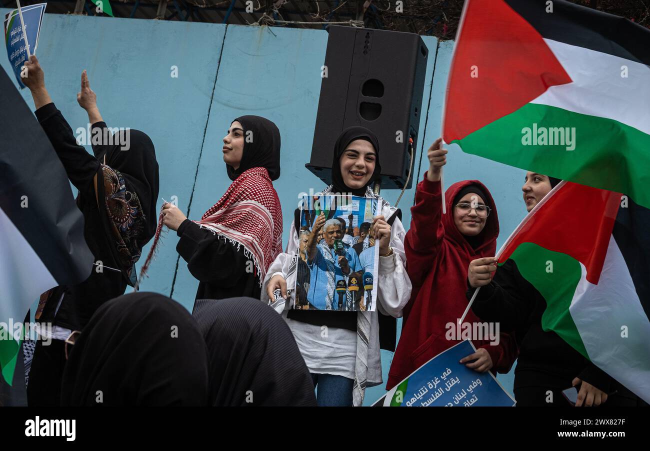 Beyrouth, Liban. 27 mars 2024. Des femmes palestiniennes brandissent des drapeaux palestiniens lors d'une manifestation à Beyrouth, Liban, le 27 mars 2024 contre le traitement prétendument réservé par l'UNRWA à ses employés pro-palestiniens. La femme au centre tient un portrait de l'ancien enseignant de l'UNRWA, Fathi al-Sharif. Al-Sharif a été suspendu de son poste pour des actions présumées "qui violent le cadre réglementaire de l'Agence régissant la conduite du personnel", a déclaré l'UNRWA à Reuters. (Photo de Collin Mayfield/Sipa USA) crédit : Sipa USA/Alamy Live News Banque D'Images