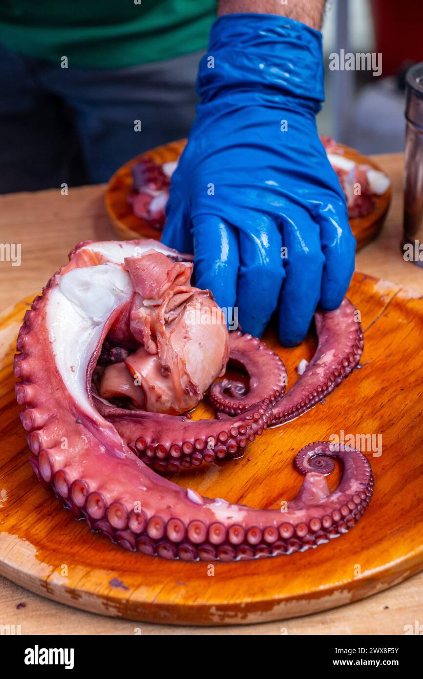 main tenant quelques tentacules de poulpe pour le couper et préparer quelques portions de 'pulpo a feira'. Banque D'Images