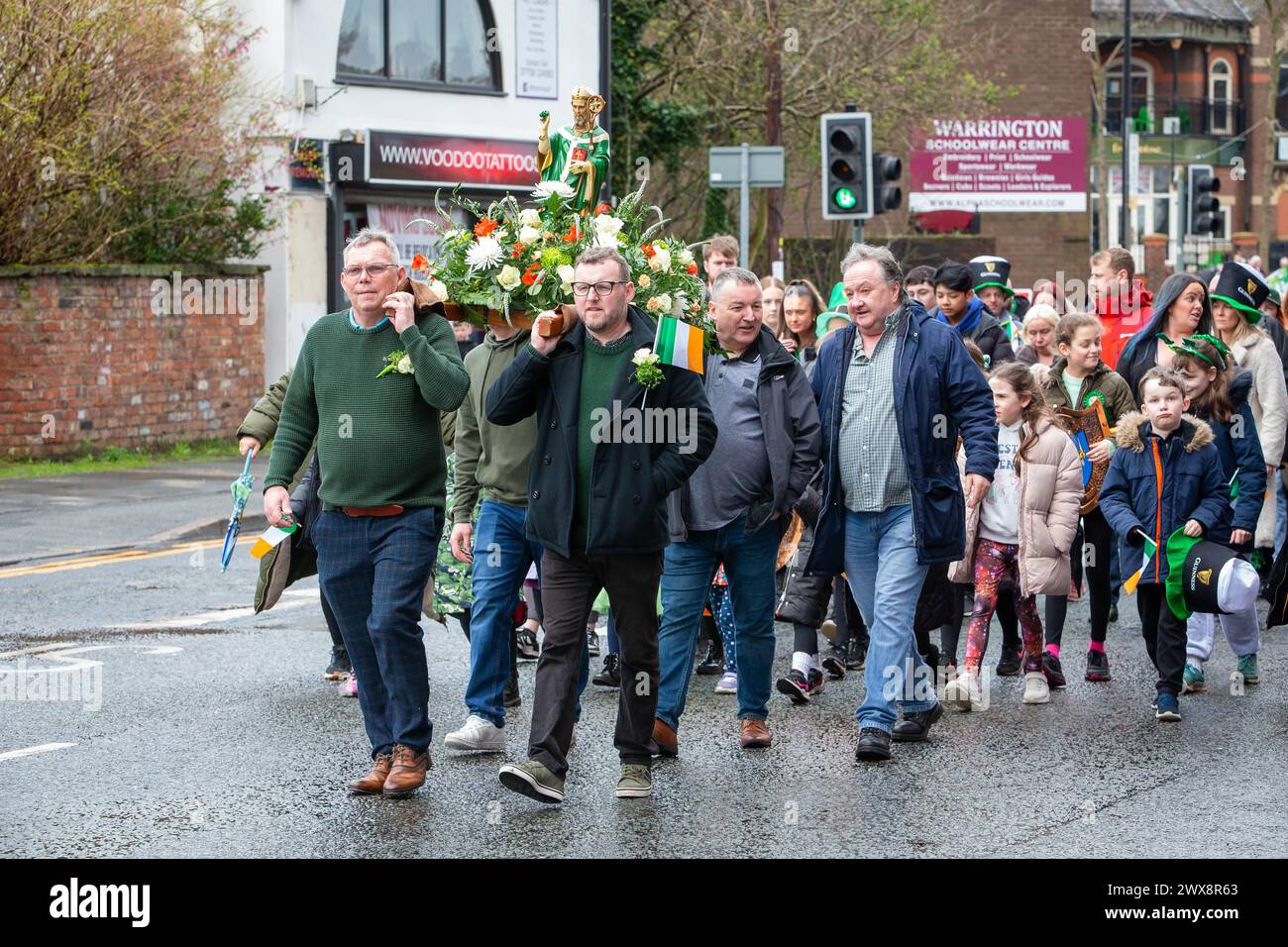 Quatre hommes portent une statue fleurie de St Patrick lors de la parade de la St Patrick en 2024 à Warrington Banque D'Images