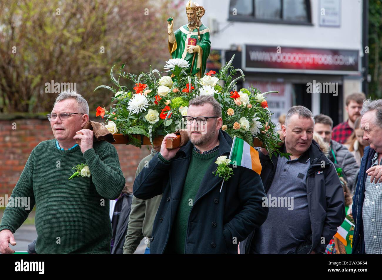 Quatre hommes portent une statue fleurie de St Patrick lors de la parade de la St Patrick en 2024 à Warrington Banque D'Images
