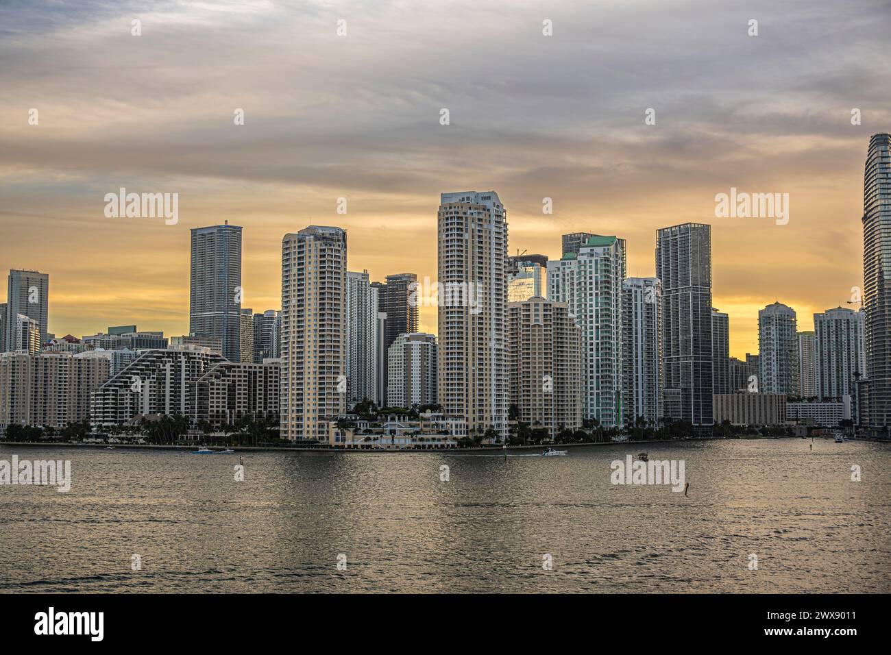 Miami, Floride, États-Unis - 29 juillet 2023 : ciel gris à jaune au-dessus des bâtiments sur l'île de Brickell Key au soir 19:47. Statue Centinel entre Teques Banque D'Images