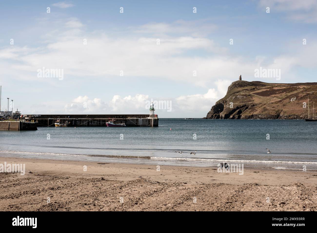 Vue lointaine de la Tour Milner et du mur du port avec feu de navigation, Port Erin, Île de Man Banque D'Images