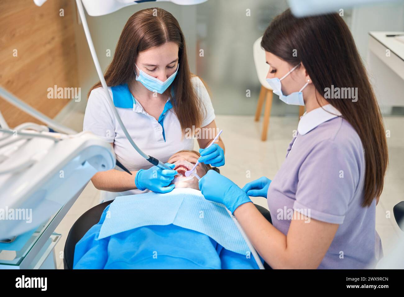 Jeune femme dentiste avec assistant traite les dents de l'adolescente Banque D'Images