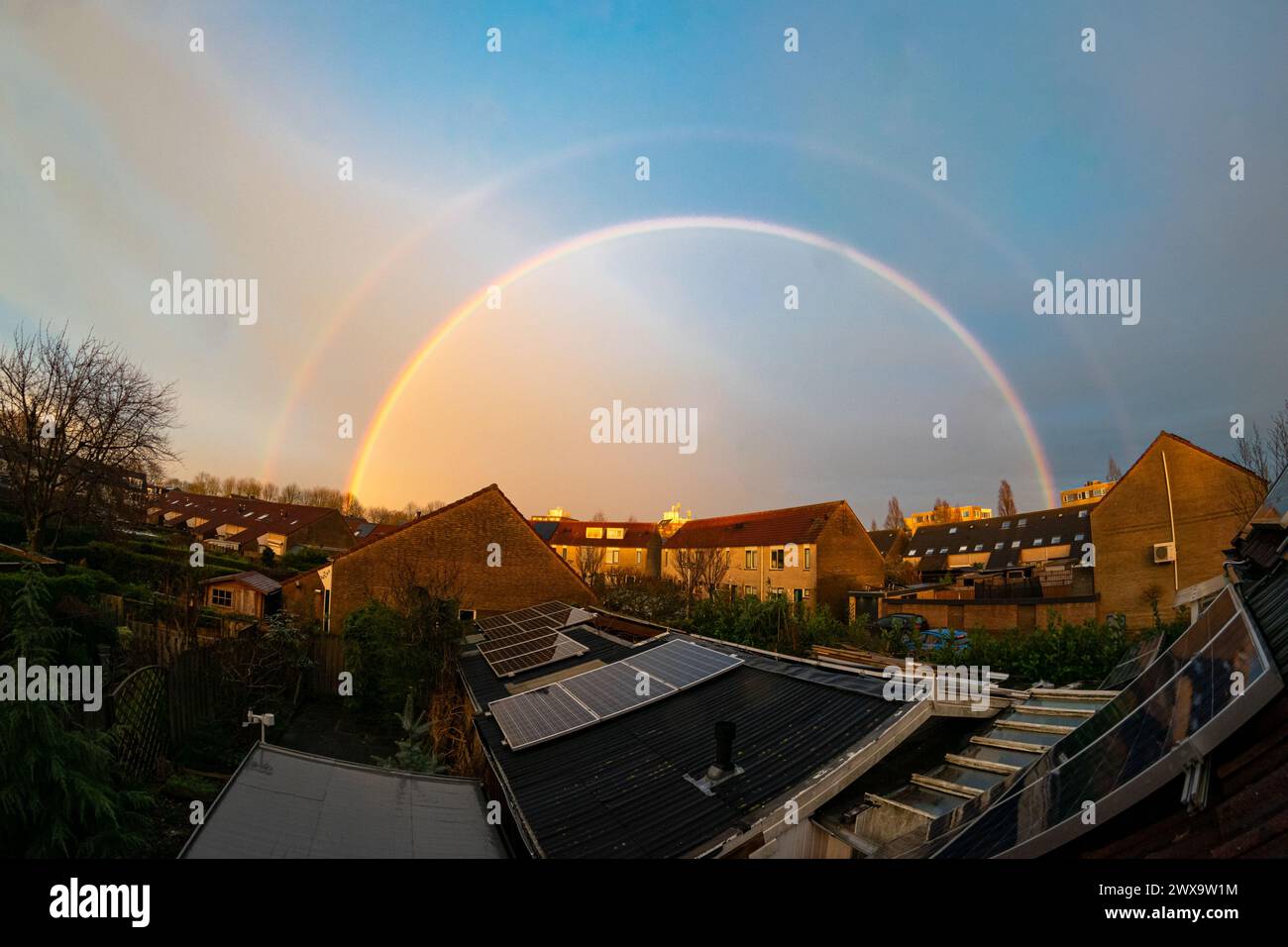 Double arc-en-ciel lumineux et complet après le passage d'un orage nocturne au-dessus d'un quartier de banlieue à Waddinxveen, aux pays-Bas. Banque D'Images