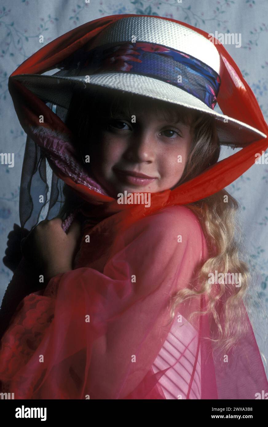 Une fille porte un chapeau alors qu'elle essaie de s'habiller avec une écharpe, Colorado, États-Unis. Banque D'Images