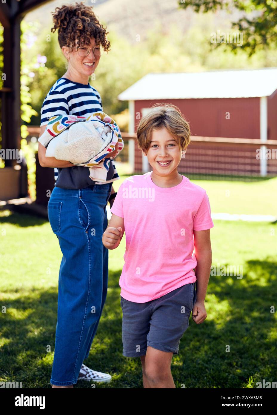 Portrait d'un garçon souriant avec mère debout sur l'herbe Banque D'Images