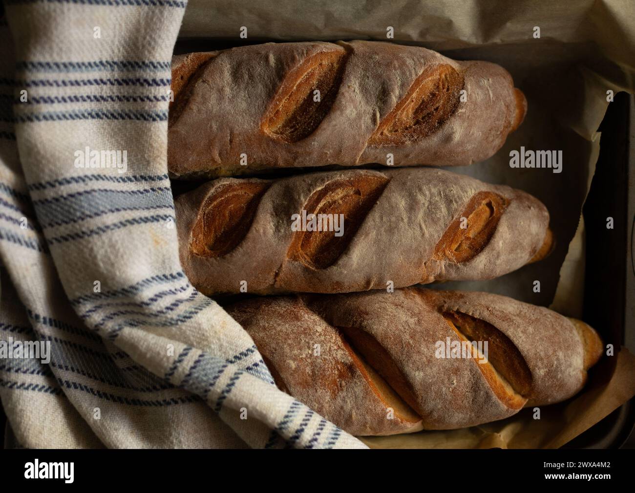 Trois baguettes sur une plaque de cuisson avec une serviette en coton. Texture du pain tranché Banque D'Images