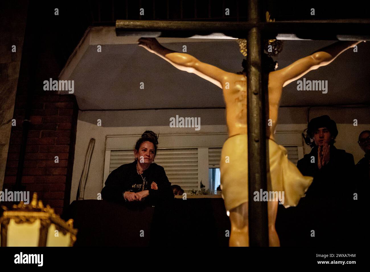 Santa Coloma de Gramenet, Espagne : le 28 mars 2024, Une femme sur un balcon regarde la procession du jeudi Saint qui a lieu à Santa Coloma de Gramenet, dans la province de Barcelone, pendant les célébrations de la semaine Sainte. Crédit : Jordi Boixareu/Alamy Live News Banque D'Images