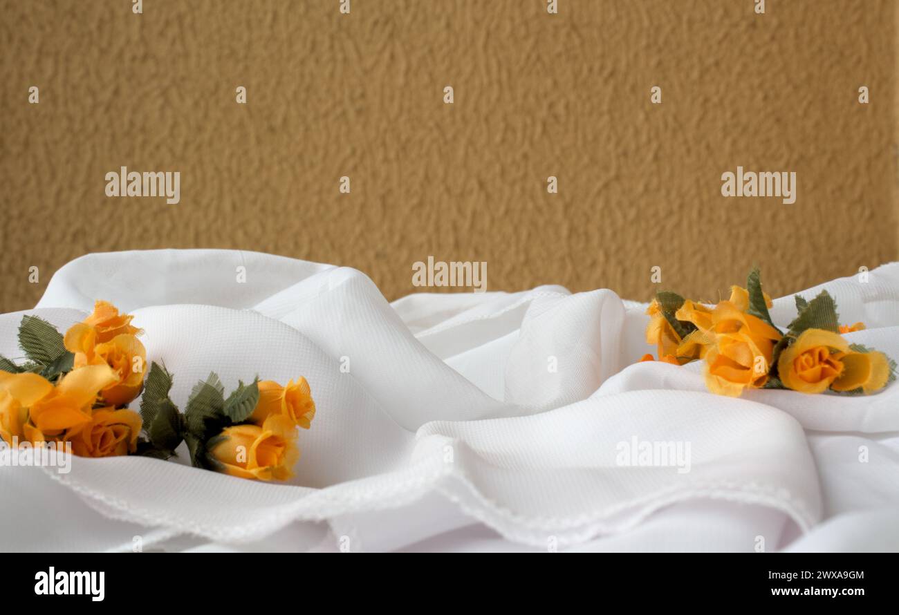 Fond horizontal avec tissu blanc et fleurs de couleur orange againe un mur de couleur moutarde Banque D'Images