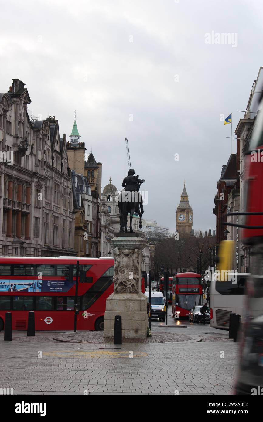 Une photographie de composition de portrait d'une scène de rue londonienne à Trafalgar Square, avec une ligne d'horizon emblématique de Big Ben, des bus londoniens, des cyclistes et des statues Banque D'Images