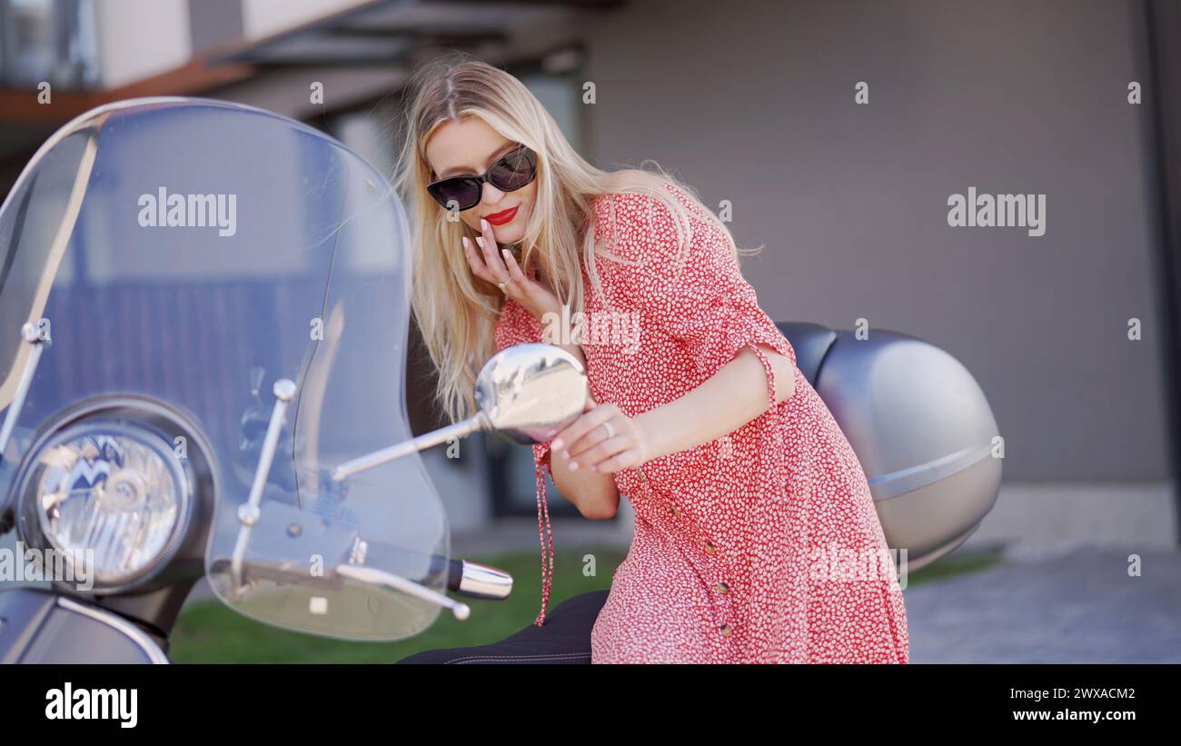 Femme à la mode s'appuyant sur un scooter Vintage à l'extérieur Banque D'Images