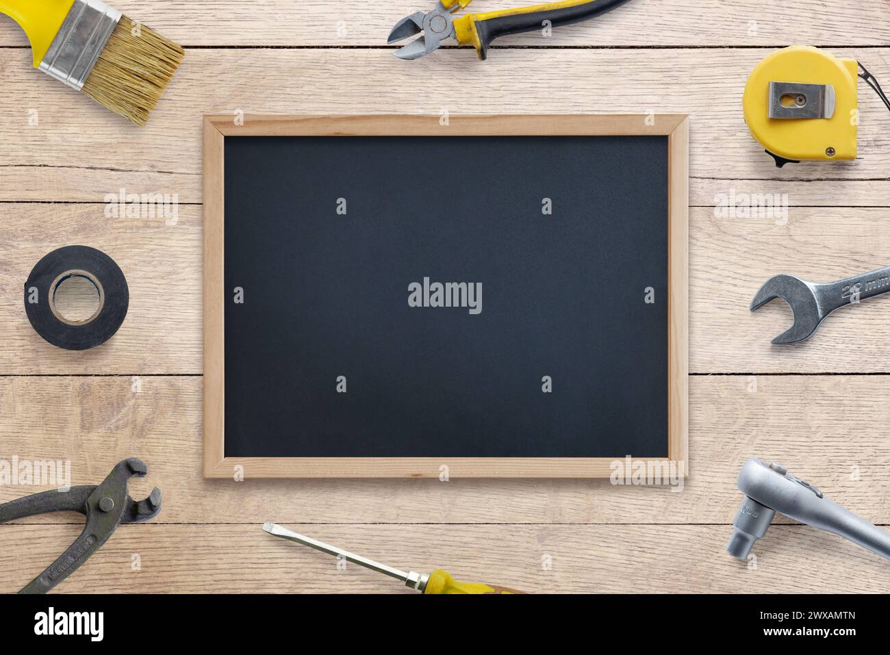 Nettoyer le tableau noir entouré d'outils : brosse, pince, tournevis, mètre ruban, ruban adhésif, clé sur table en bois. Parfait pour le texte, logo promotio Banque D'Images
