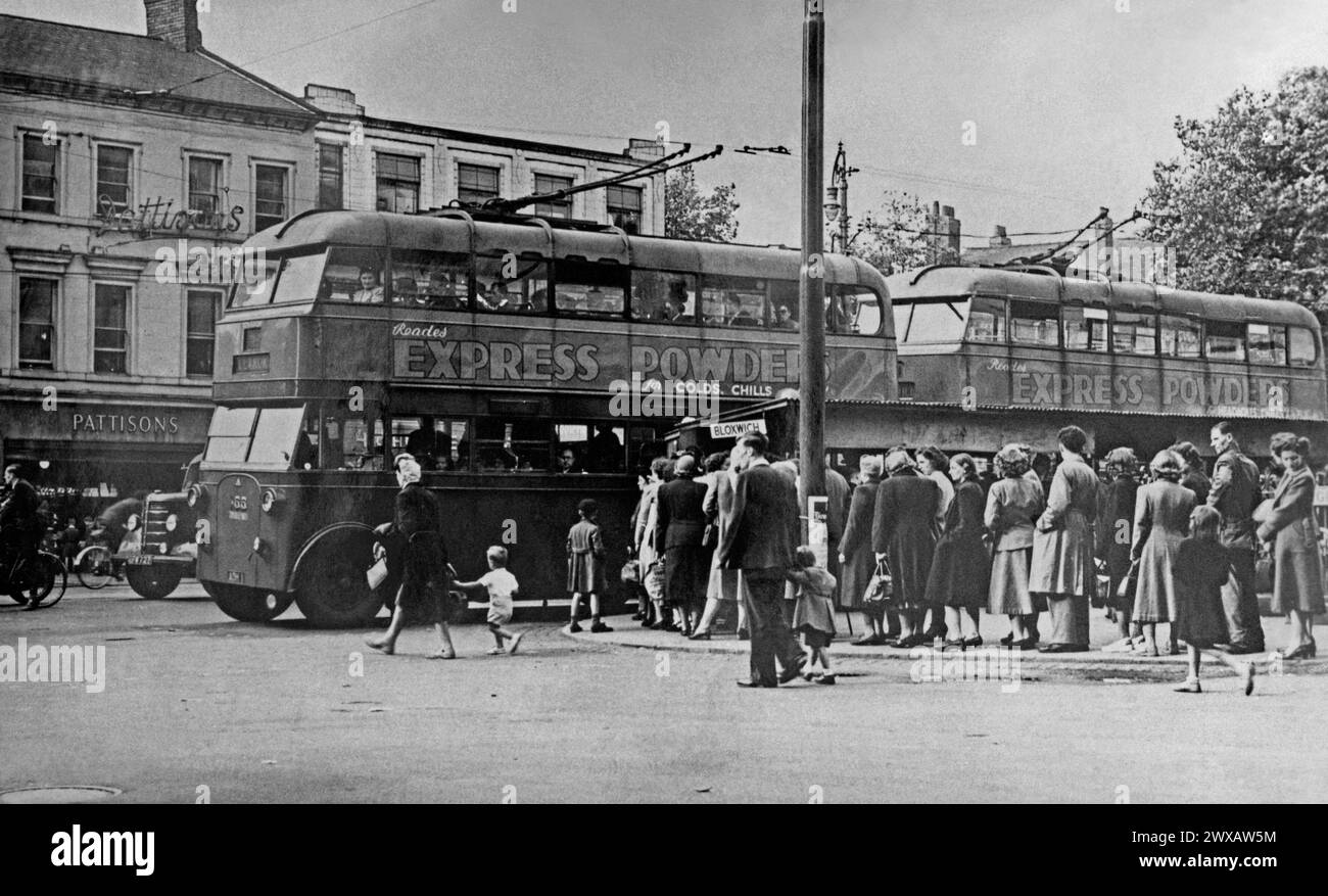 Une scène animée à l'arrêt de bus à The Bridge à Walsall, West Midlands, Angleterre, Royaume-Uni c. 1950. La longue file d'attente s'est formée, attendant un trolleybus pour les emmener à Bloxwich. Le trolleybus 155 (au centre gauche) était un Sunbeam MS2 entré en service en 1933. Il a été retiré en 1951.Walsall centre-ville avait de nombreux magasins, y compris Pattisons, une pâtisserie (à gauche). Ceci est tiré d'un vieil album de photographies - une photographie vintage des années 1940/50. Banque D'Images