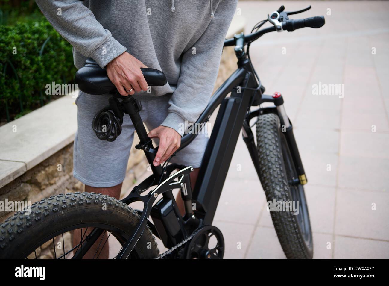 Vue rognée. Homme cycliste ajustant un siège sur un vélo alimenté par batterie avant de rouler. Louer un vélo électrique comme transport urbain écologique. Les gens. AC Banque D'Images