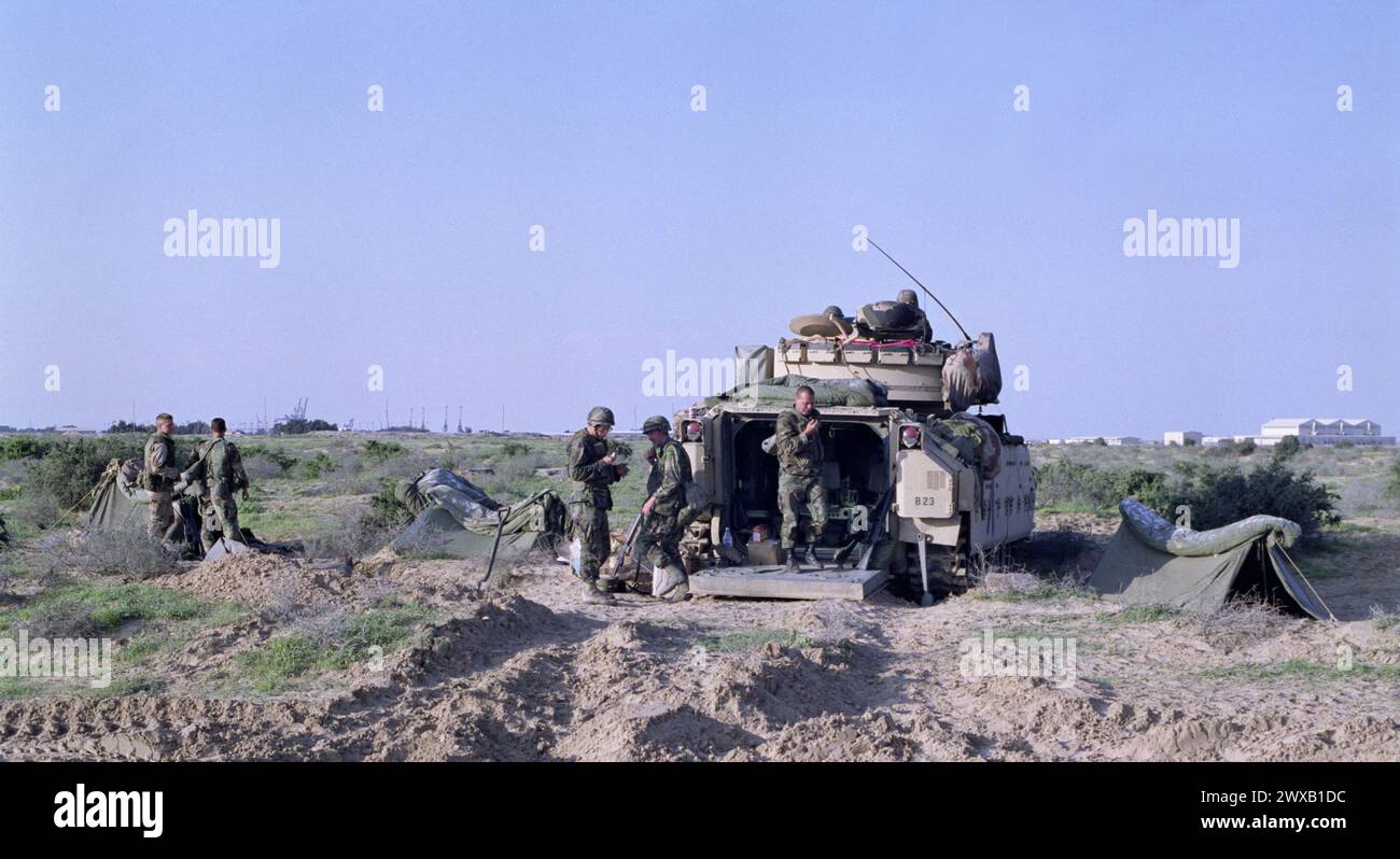 25 mars 1991 des soldats de l'armée américaine de la 5ème division blindée bivouaquèrent à côté de leur véhicule de combat Bradley Cavalry, à la frontière dans le nord du Koweït. Banque D'Images