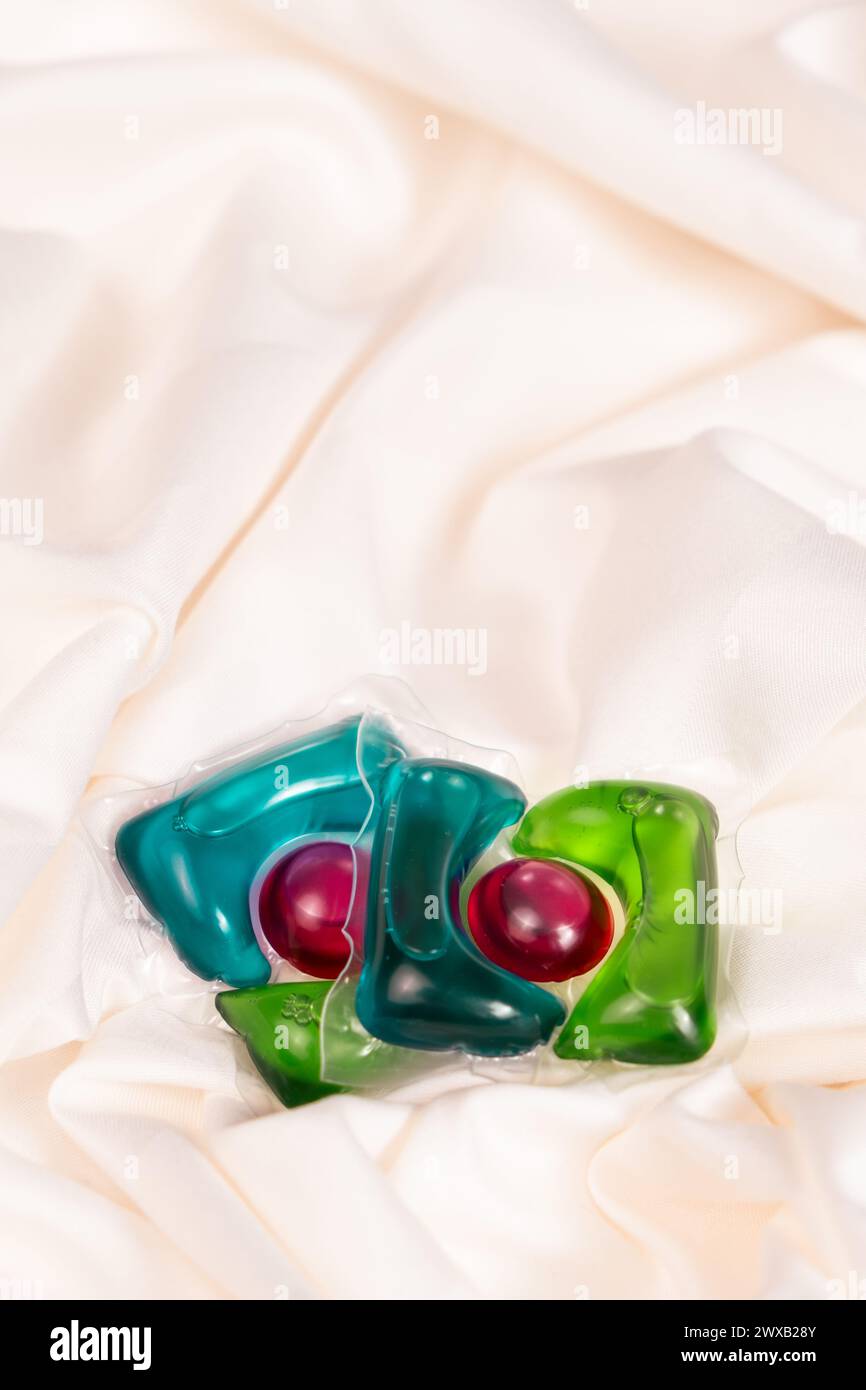 Gel détergent liquide en capsules sur le tissu gros plan, espace pour le texte. Banque D'Images