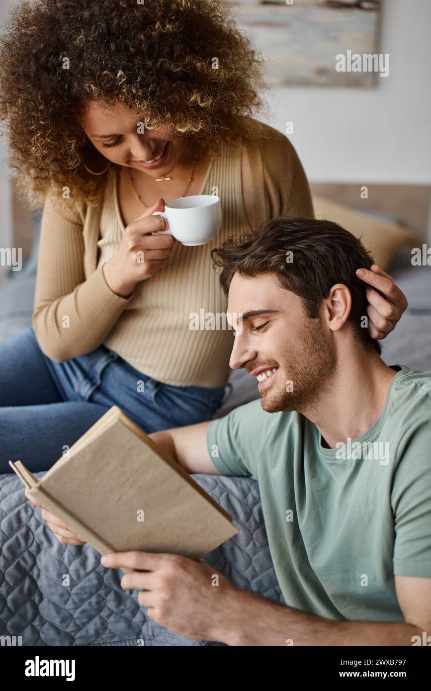 jeune femme bouclée et brune homme se livrent à une conversation animée autour d'un café, livre dans ses mains Banque D'Images