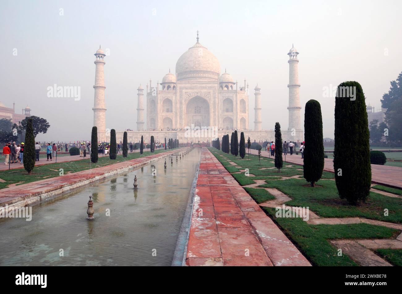 Le Taj Mahal dans la brume tôt le matin avec des visiteurs et des jardins paysagers au premier plan, site du patrimoine mondial de l'UNESCO, Agra, Uttar Pradesh, Inde Banque D'Images