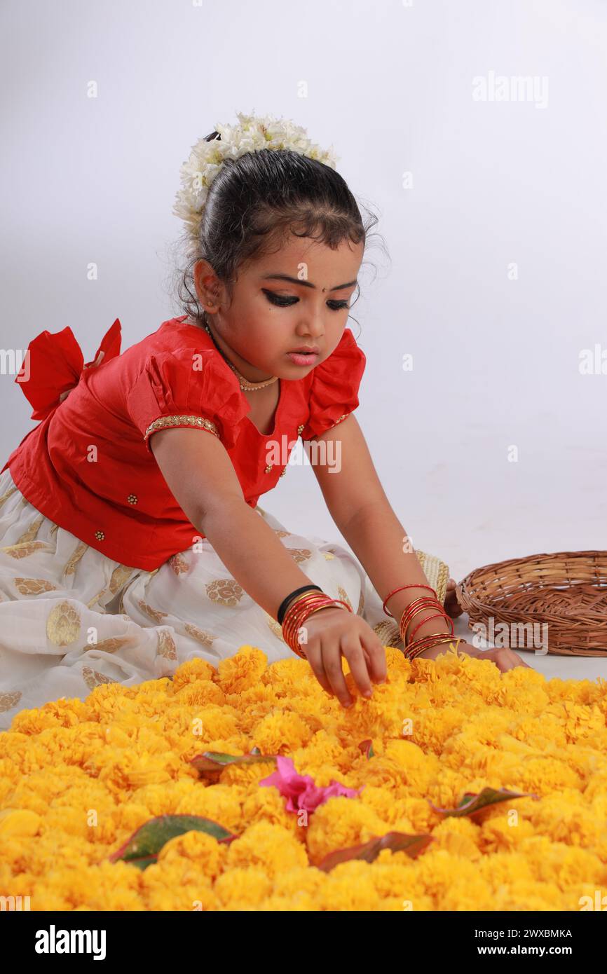 Un enfant mignon petite fille portant robe Kerala-robe-couleur dorée jupe longue et chemisier rouge, thème du festival onam, fond blanc isolé. Banque D'Images