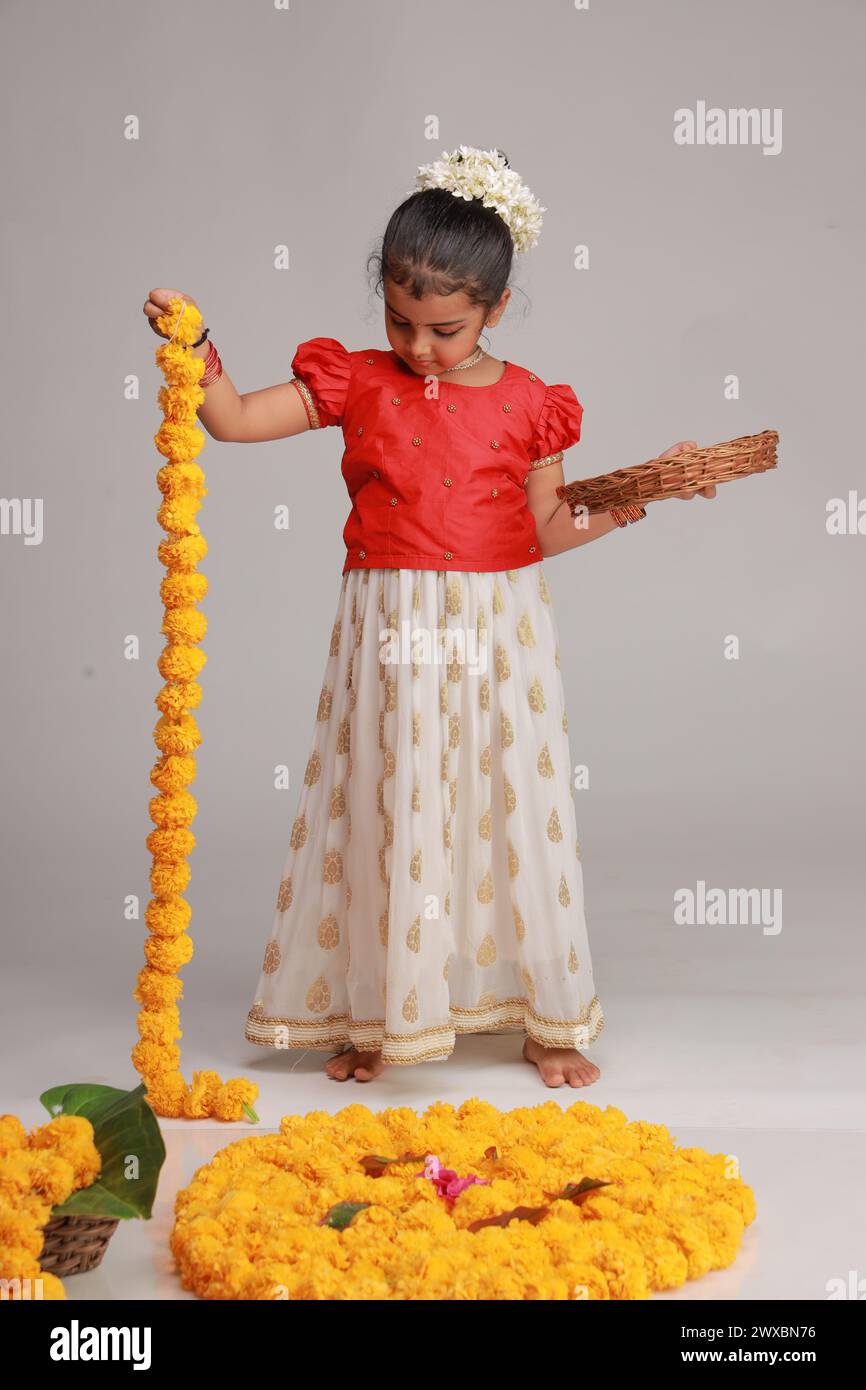 Un enfant mignon petite fille portant robe Kerala-robe-couleur dorée jupe longue et chemisier rouge, thème du festival onam, fond blanc isolé. Banque D'Images